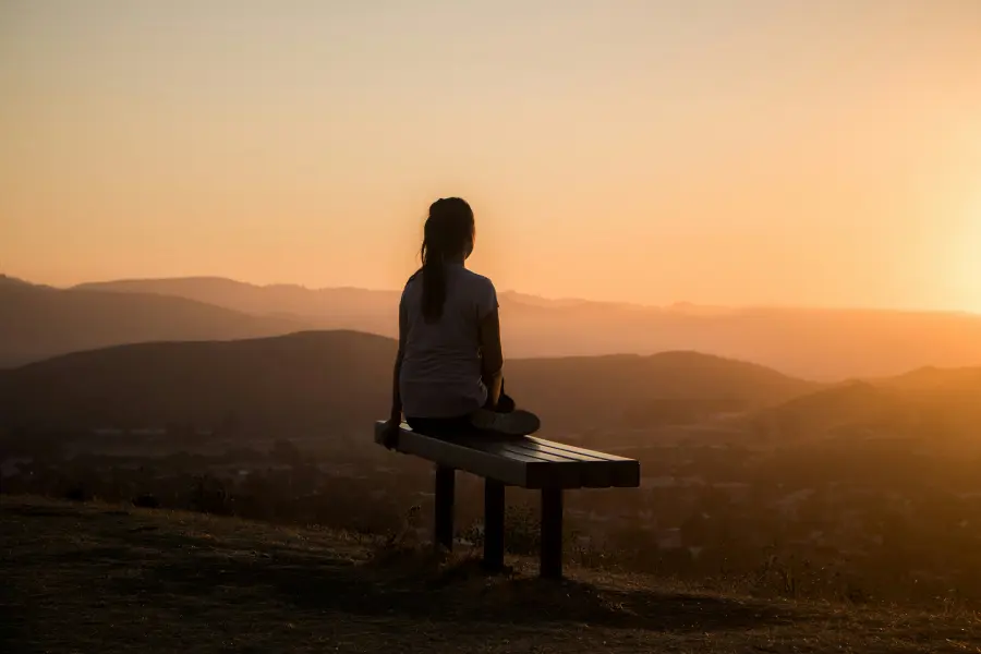 A lady meditating as the sunsets over the mountains