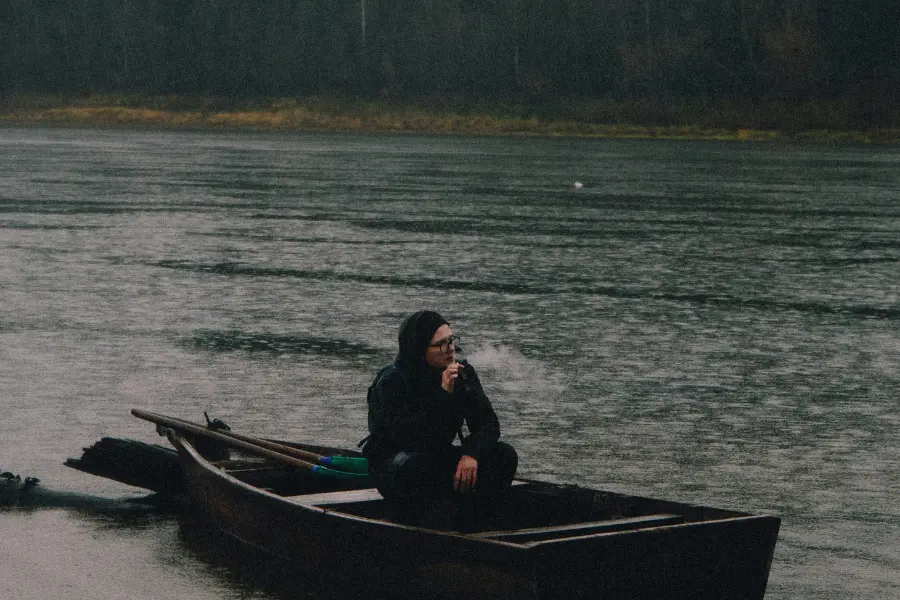 An image of a man sitting on a boat in a lake. Nature rowing.